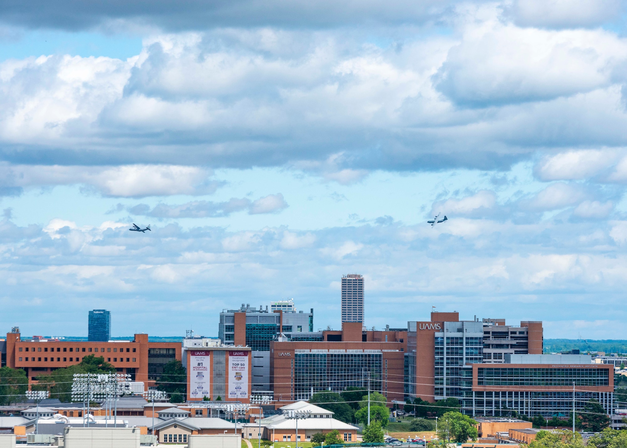 People watch as two C-130s fly over the city