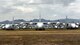 A photo of various C-130 Hercules carrier aircraft with mountains behind them