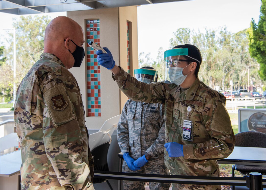 Senior Airman Avery Lake, 30th Medical Group mental health technician, checks the temperature of Gen. Jay Raymond, U.S. Space Force Chief of Space Operations and U.S. Space Command commander, before entering the 30th MDG for a tour, May 7, 2020, at Vandenberg Air Force Base, Calif. During the visit, Raymond observed and commended the members of Vandenberg AFB for their response to the COVID-19 global pandemic. (U.S. Air Force photo by Senior Airman Aubree Owens)