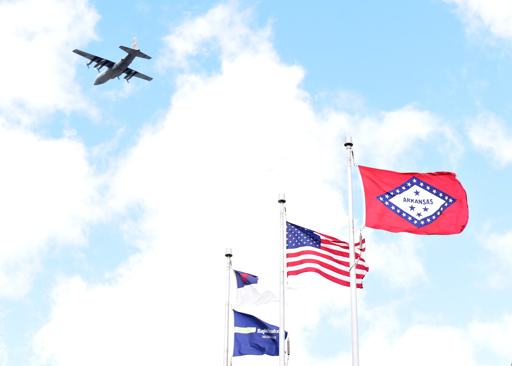 Spectators watch as two C-130s fly over the city