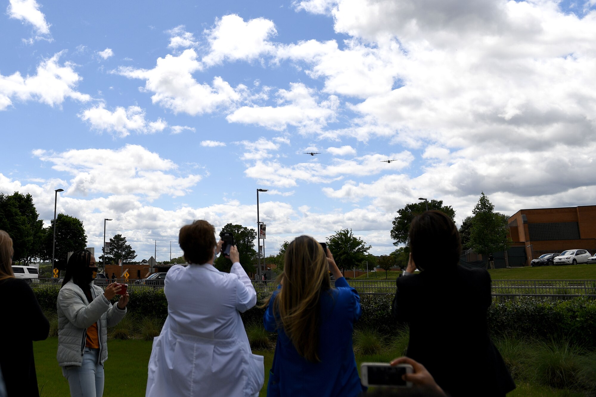 Spectators watch as two C-130s fly over the city