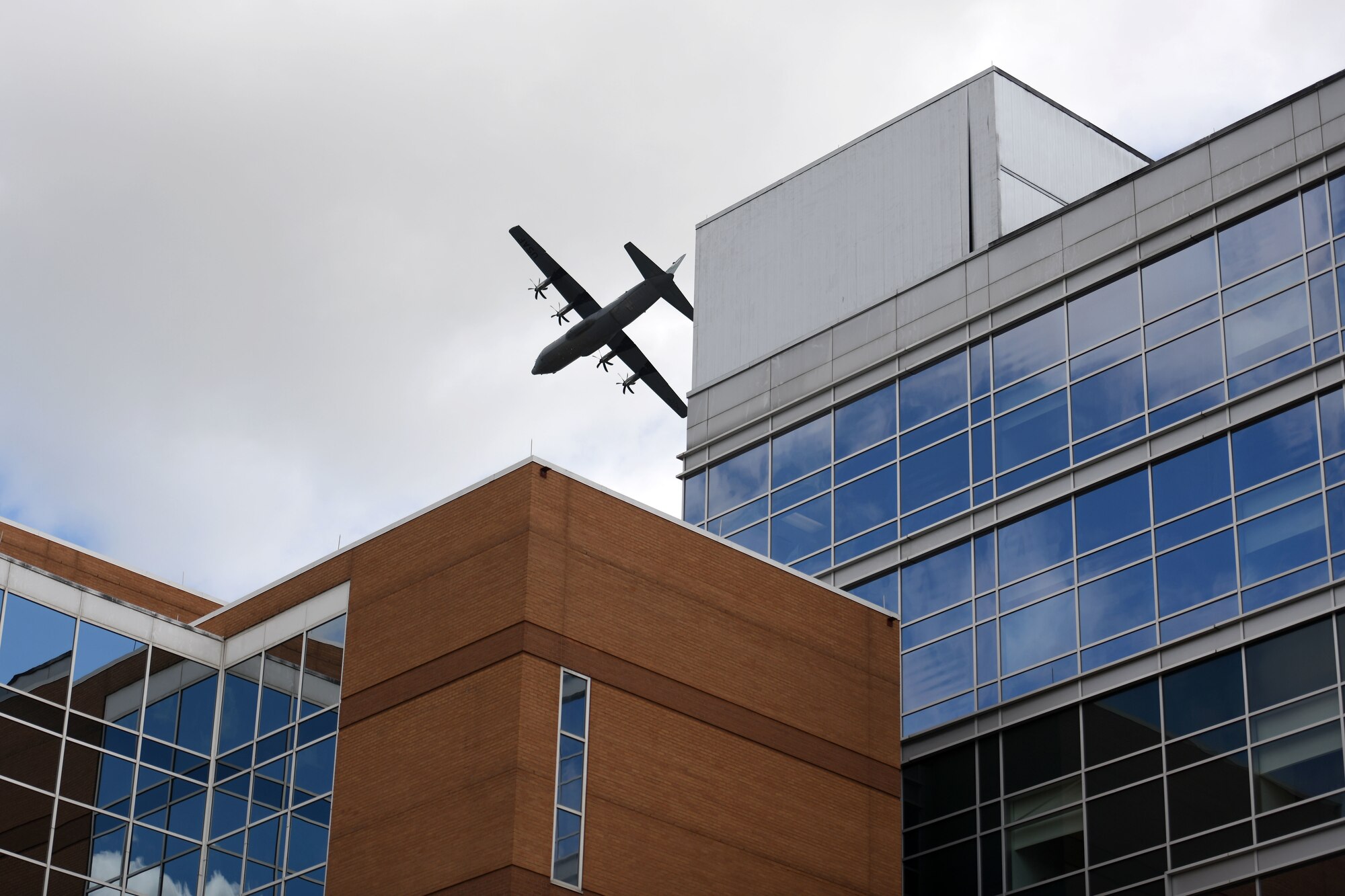 Spectators watch as two C-130s fly over the city