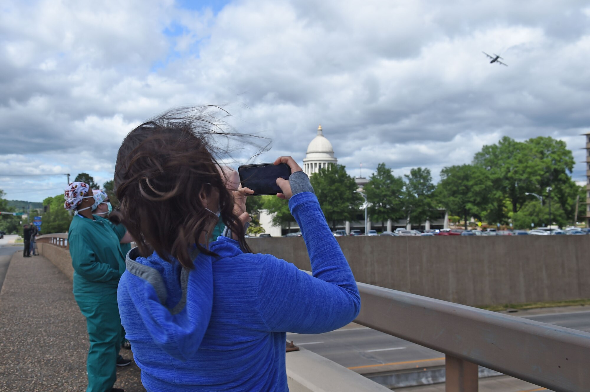 Spectators watch as two C-130s fly over the city