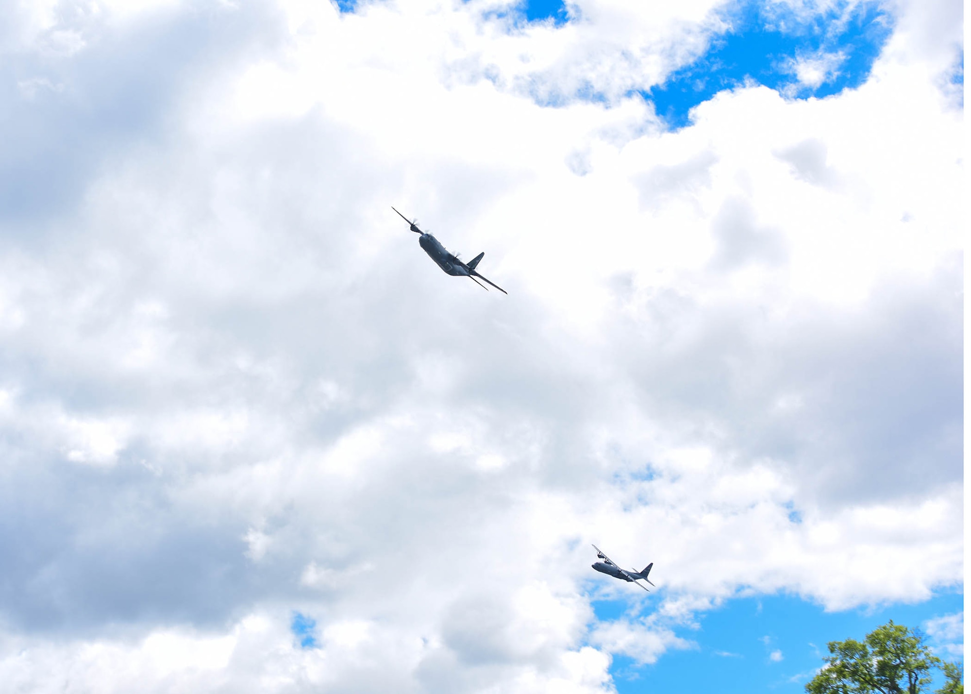 Spectators watch as two C-130s fly over the city