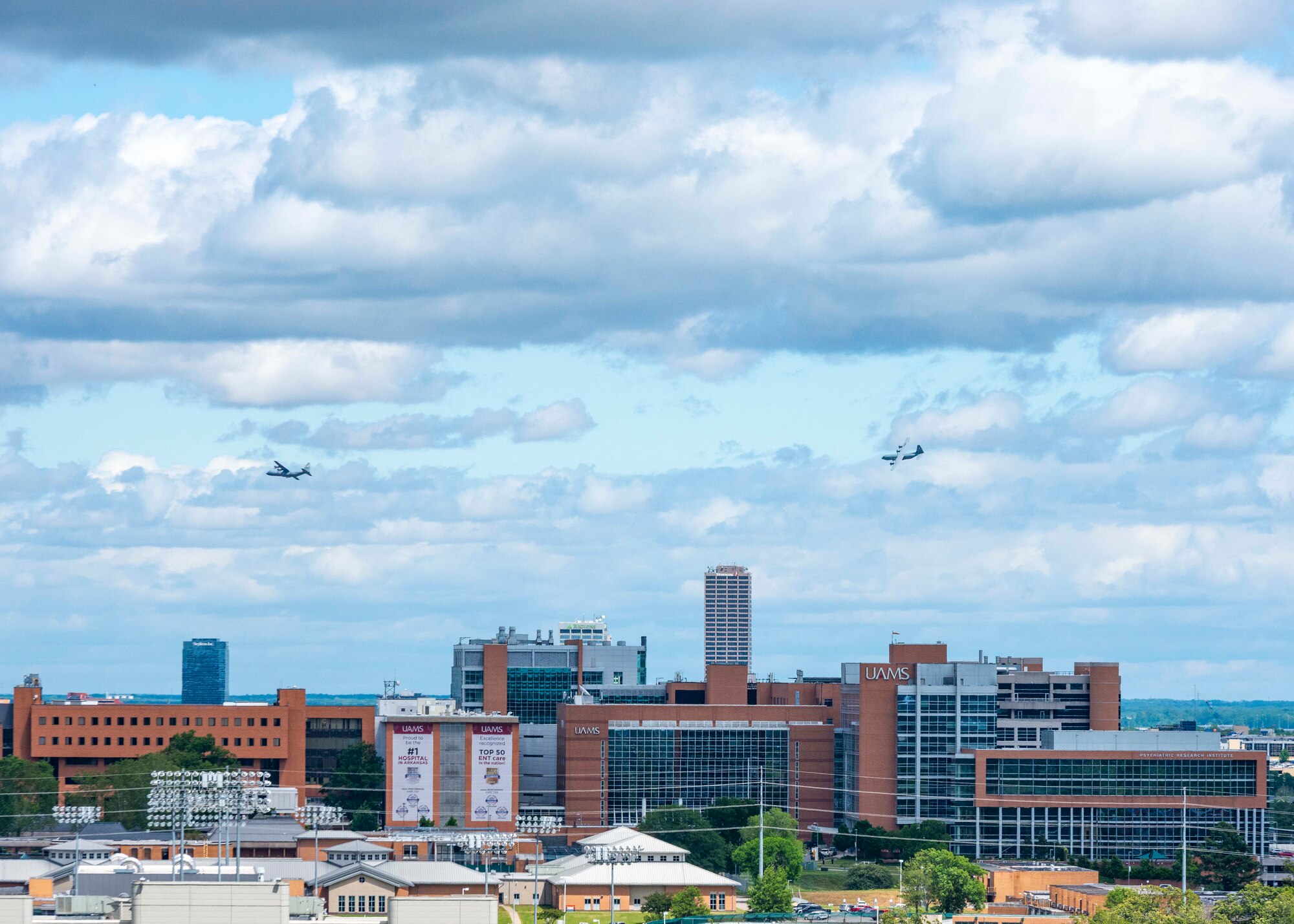 People watch as two C-130s fly over the city