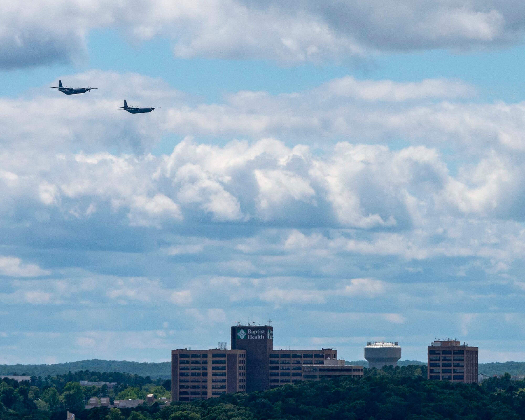 People watch as two C-130s fly over the city