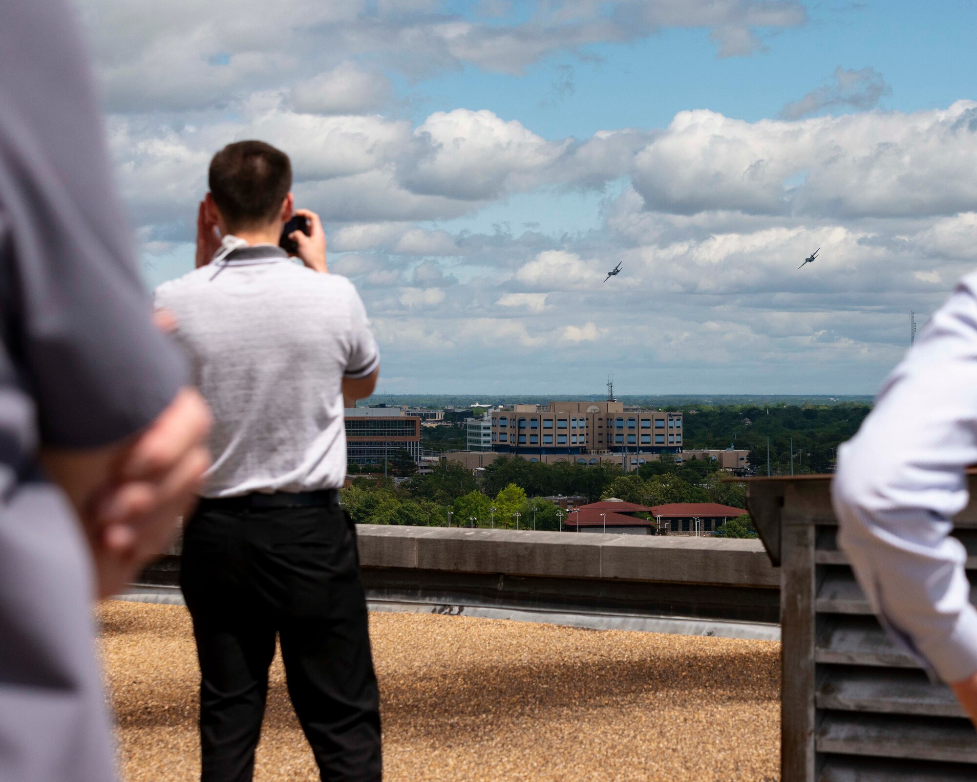 People watch as two C-130s fly over the city