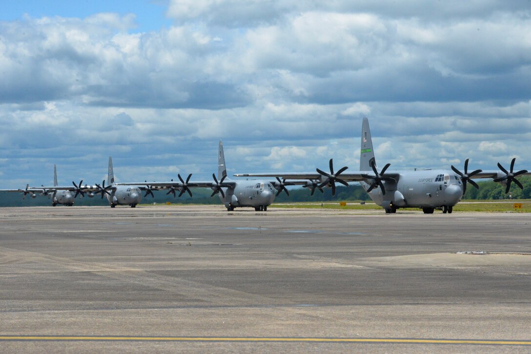 four C-130s taxi on the flight line