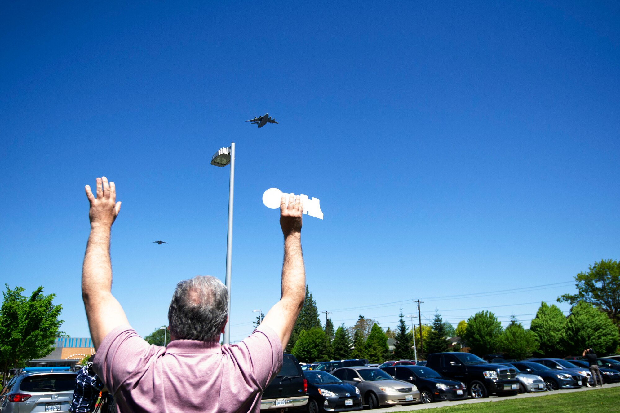 A Providence Regional Medical Center employee waves his hands at the two-ship C-17 Globemaster III formation May 8, 2020 in Everett, Washington. The 62nd Airlift Wing, based out of Joint Base Lewis-McChord, Wash., saluted American heroes who are on the frontline in the fight against COVID-19 with a morale flyover in the state’s Puget Sound region. In January, Providence was the first U.S. hospital to report a COVID-19 case. (U.S. Air Force photo by Maj Candice Allen)
