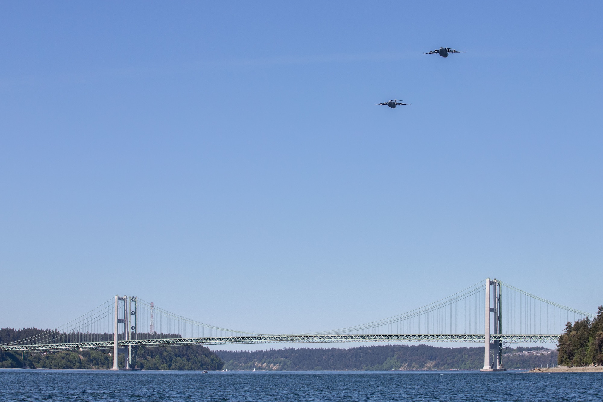 Two C-17 Globemaster IIIs assigned to the 62nd Airlift Wing conduct an Air Force Salutes morale flyover above the Tacoma Narrows Bridge in Tacoma, Wash., May 8, 2020. The flyover honored the American heroes at the forefront in the fight against COVID-19. (U.S. Air Force photo by Staff Sgt. Joshua Smoot)