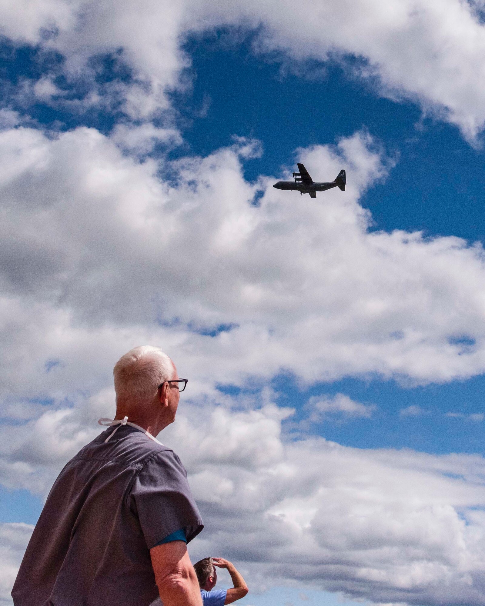 People watch as two C-130s fly over the city