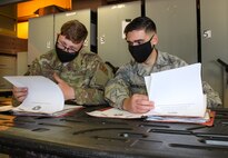 Senior Airman Wyatt Hart, 50th Security Forces base defense operations center controller, left, and Senior Airman Brian Calenda, 50th SFS response force leader, review files of paperwork May 7, 2020 at Schriever Air Force Base, Colorado. The folders include paperwork required for Airmen when they deploy. (U.S. Air Force photo by Marcus Hill)