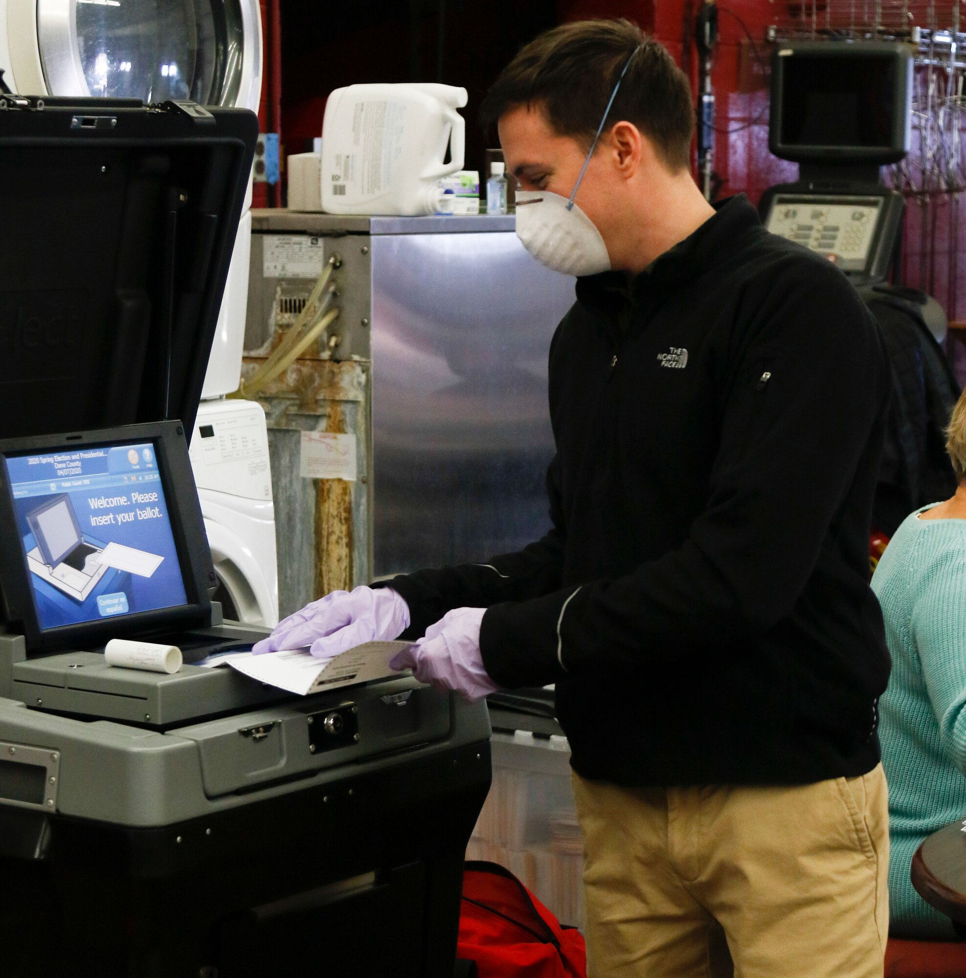 1st Lt. John Moore, an Infantry Officer with the 2-127th Infantry Regiment, helps feed ballots as a poll worker in Fitchburg, Wis., April 7, 2020.