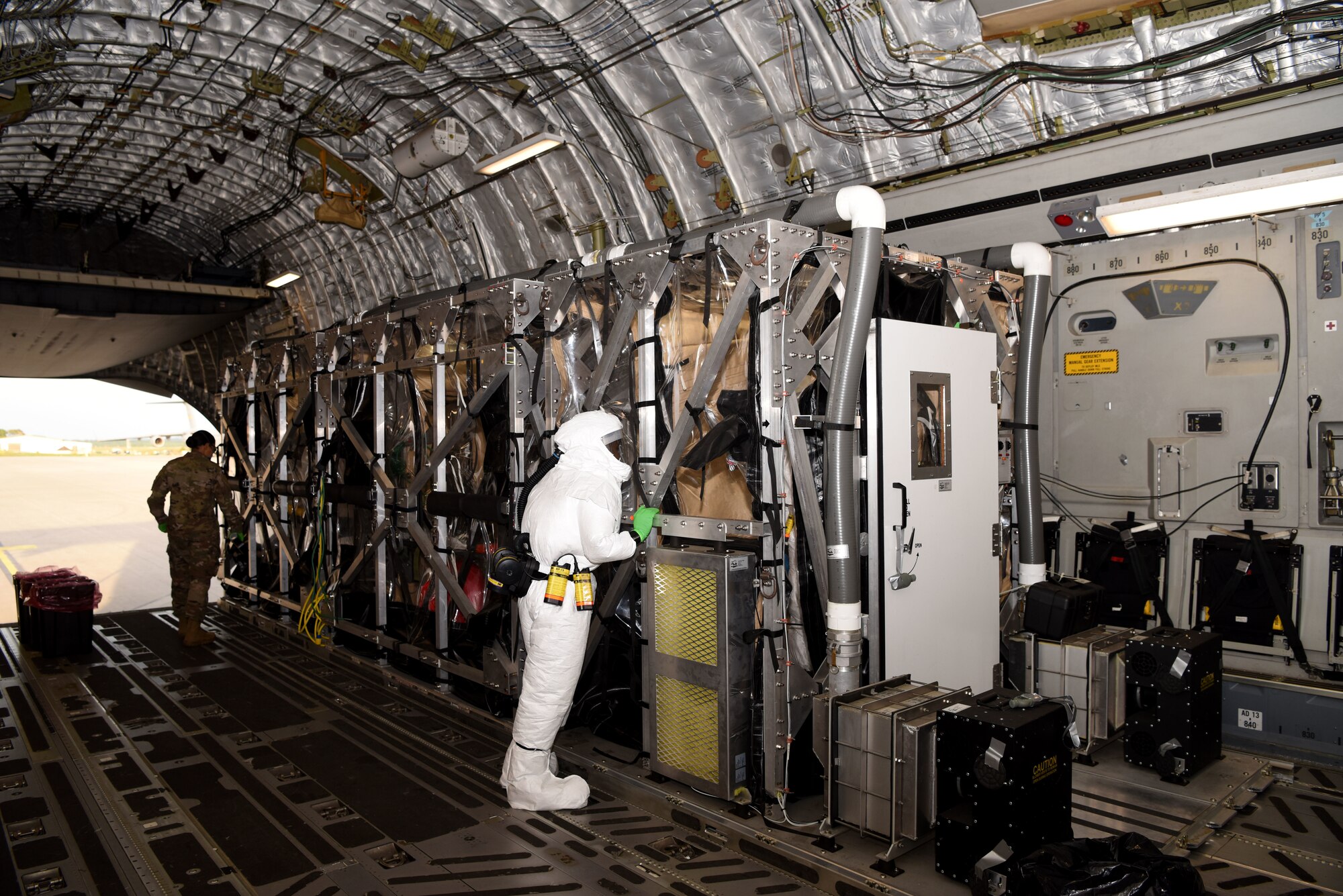 U.S. Air Force Senior Airman Enock Koech, 313th Expeditionary Operations Support Squadron, watches the decontamination of a Transport Isolation System on a U.S. Air Force C-17 Globemaster III aircraft.