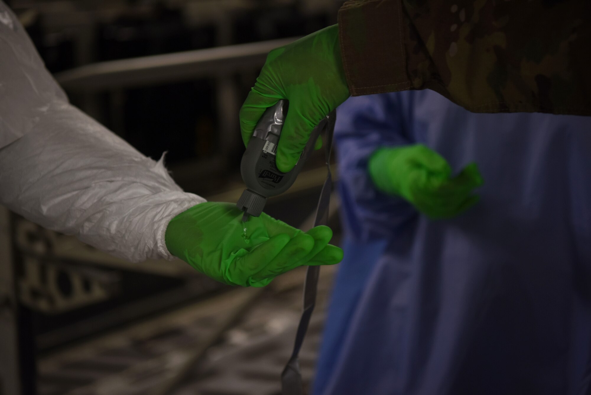 U.S. Air Force Airmen assigned to the 521st Air Mobility Operations Wing sanitize their hands after decontaminating a Transport Isolation System on a U.S. Air Force C-17 Globemaster III aircraft.