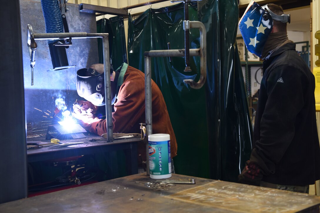 U.S. Air Force Airman 1st Class Stephen Thomas, 786th Civil Engineer Squadron structures, left, fuses metal while receiving instructions from Staff Sgt. Jared Swan, 435th Construction and Training Squadron contingency instructor, during a welding course.