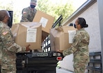 Members of the Texas Military Department's Joint Task Force 176 – Texas State Guard Pfc. Jason Hunter, Texas National Guard Capt. Stephanie Enloe, the task force's medical operations officer, and Sgt. 1st Class Rajendran Kumaraswamy, the task force's medical noncommissioned officer – unload disinfecting kits for Soldiers preparing to support long-term care facility disinfection operations at Camp Mabry in Austin, Texas, May 7, 2020.