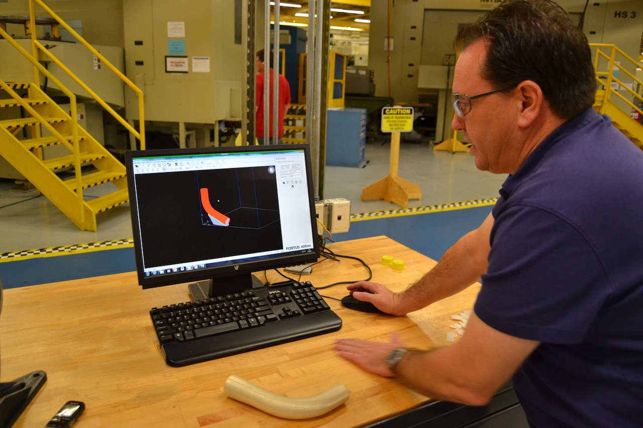 A technician shows a 3D-printed part for a small aircraft.