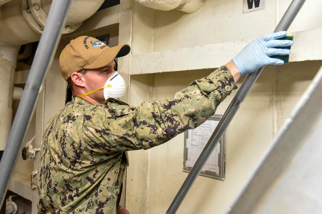 A sailor cleaning a handrail.