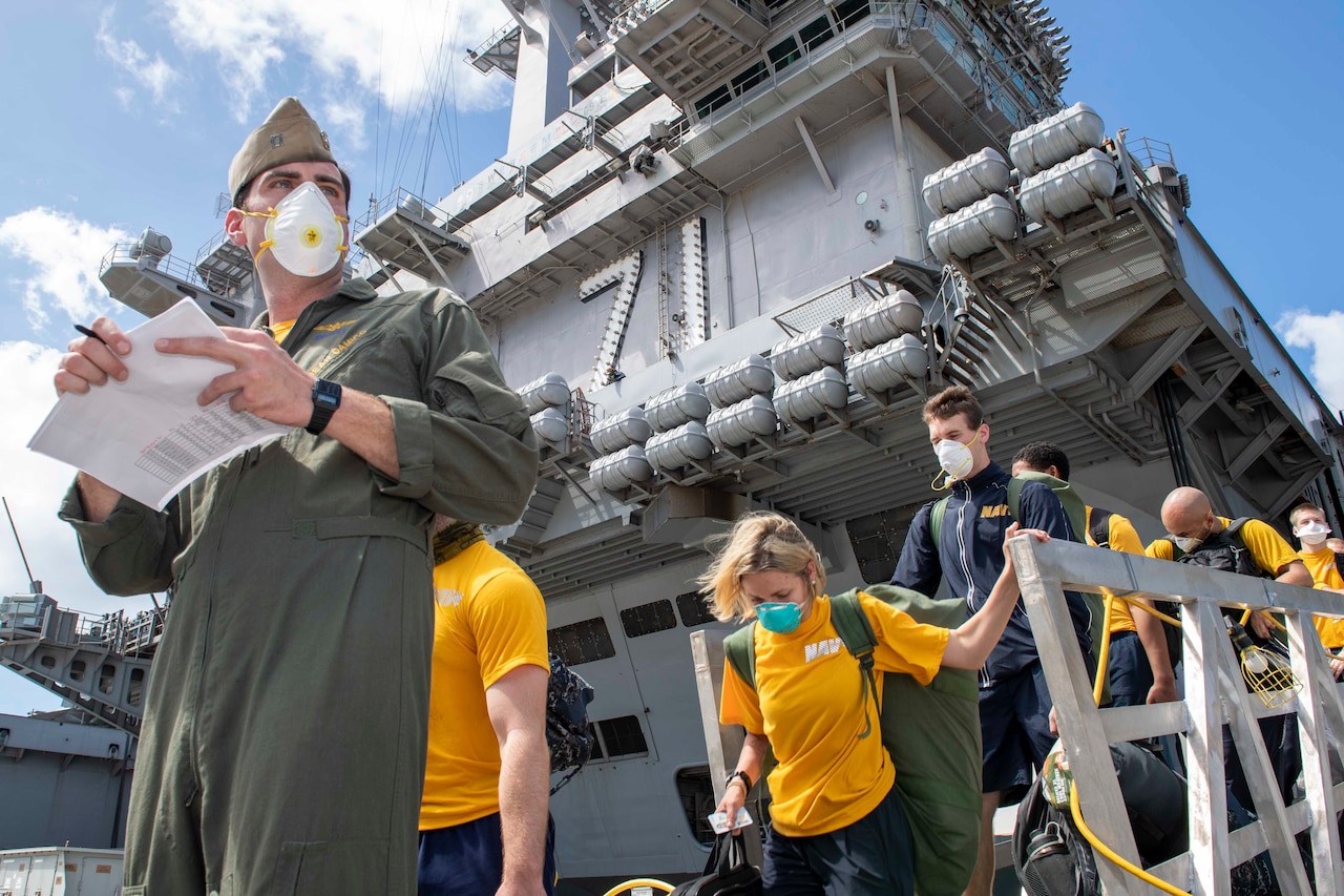 Sailors disembarking an aircraft carrier.