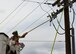 Photo of a electrical systems shop Airman stands in a truck manlift while performing emergency maintenance on an electric pole