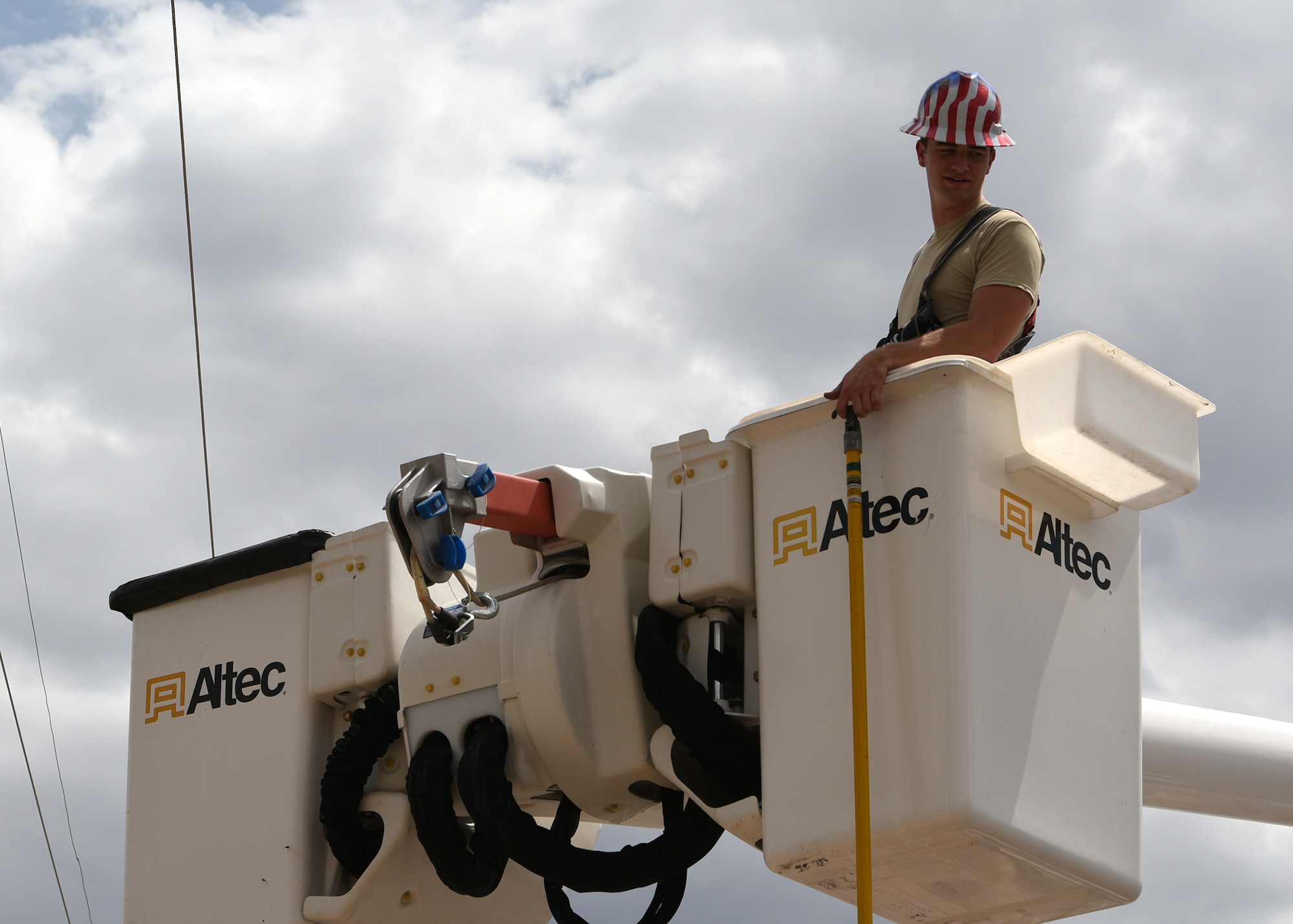 Photo of a electrical systems shop Airman stands in a truck manlift while performing emergency maintenance on an electric pole