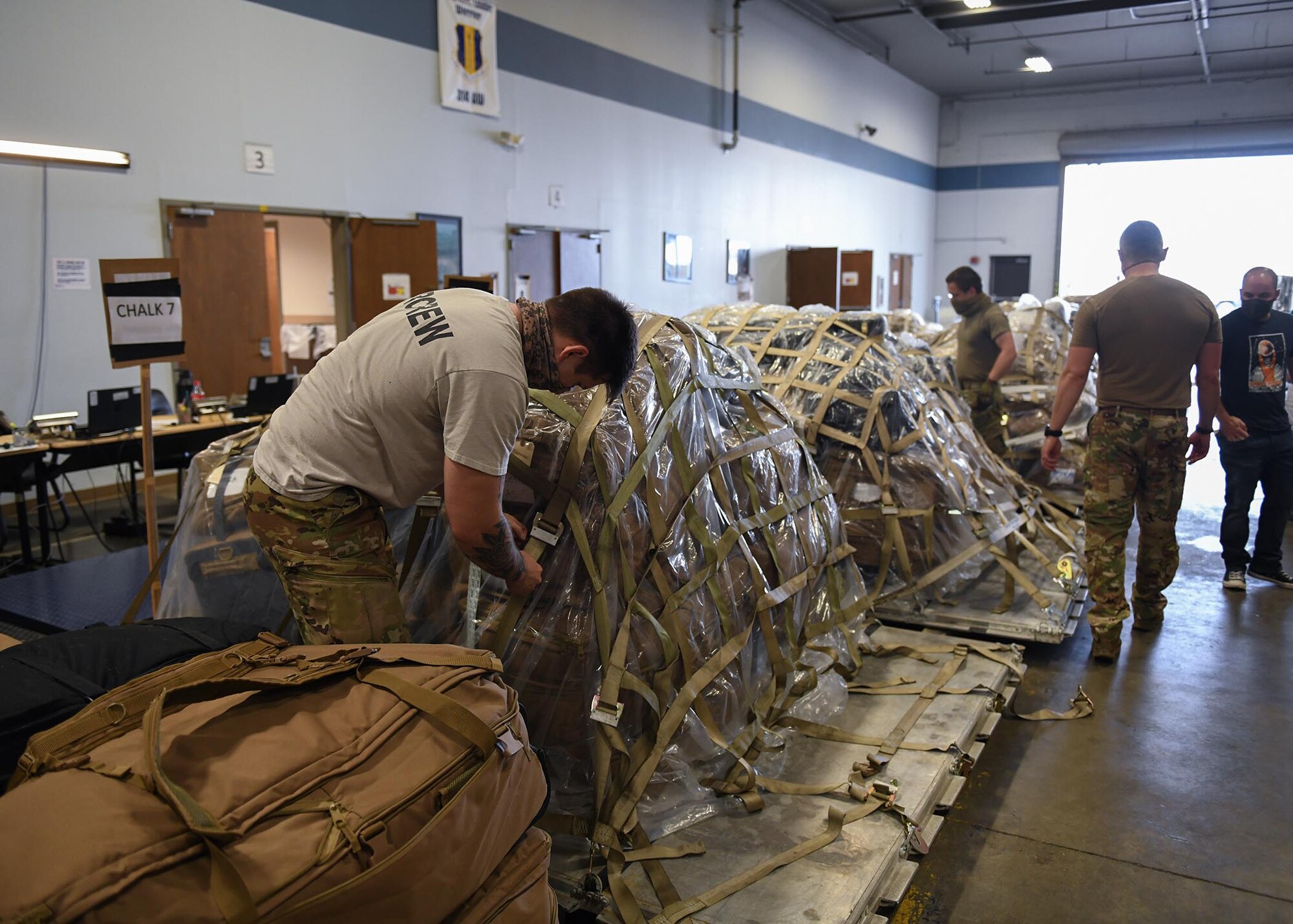 Individuals prepare tags and pallets of cargo for deploying personnel.