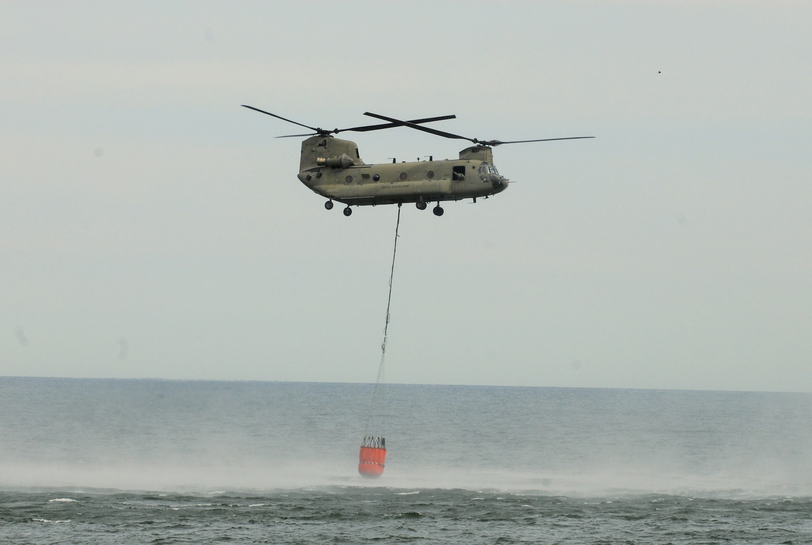 A New York Army National Guard CH-47 Chinook helicopter hauls 2,000 gallons of water out of Lake Ontario in a bucket near Hamlin, New York, May 6, 2020. The Chinook's pilots and crew were practicing scooping and dumping water in preparation for firefighting missions.