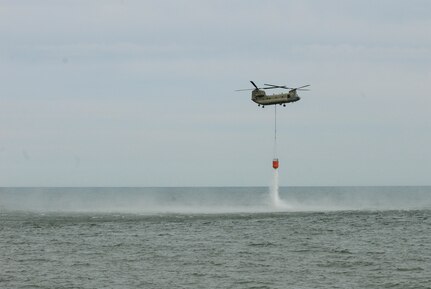 A New York Army National Guard CH-47 Chinook helicopter dumps 2,000 gallons of water from a bucket over Lake Ontario near Hamlin, New York, May 6, 2020. The Chinook's pilots and crew were practicing scooping and dumping water in preparation for firefighting missions.