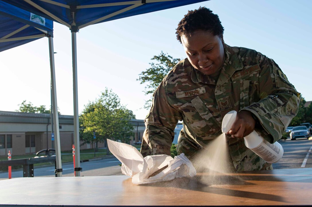 Photo of Airmen sanitizing a table for a COVID-19 Tier 2 screening.