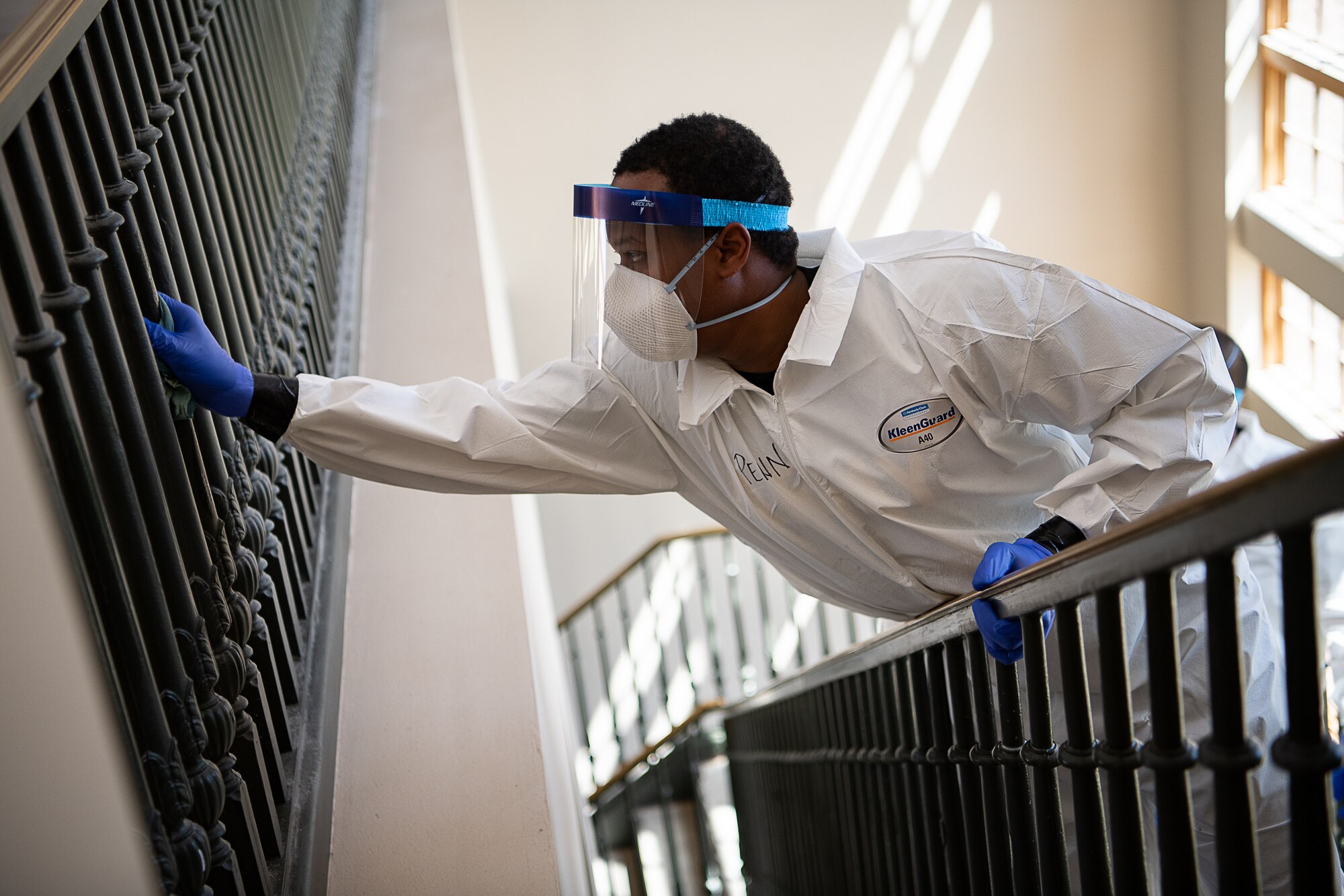 An Oklahoma Army National Guardsman leans over the bannister of a stairway to disinfect the railing of an open stairwell of the Norman Veterans Center in Norman, Oklahoma, April 29, 2020. Guardsmen were at the Center to disinfect commonly touched surfaces and high traffic areas including handrails, chair arms, tables, switches and elevator buttons, split up into three teams, in order to more efficiently covering all of the common areas of the 275,000 square-foot facility. Using pressure sprayers and hand sprayers filled with Centers for Disease Control and Prevention-approved disinfectants, the teams worked from the back of the facility to the front. The residents’ military service spans from World War II to Operation Desert Storm. (U.S. Air National Guard photo by Tech. Sgt. Kasey M. Phipps)