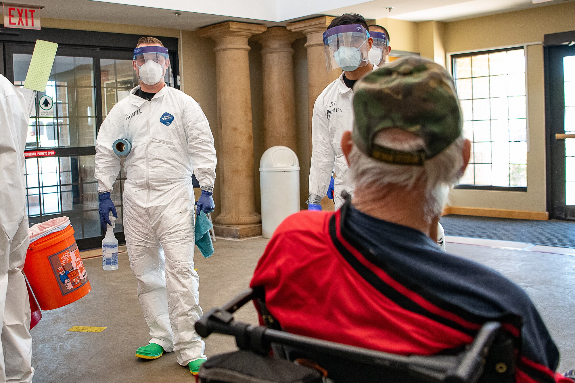 Oklahoma Army National Guardsmen speak with a resident of the Norman Veterans Center in Norman, Oklahoma, April 29, 2020. Guardsmen were at the Center to disinfect commonly touched surfaces and high traffic areas including handrails, chair arms, tables, switches and elevator buttons, split up into three teams, in order to more efficiently covering all of the common areas of the 275,000 square-foot facility. Using pressure sprayers and hand sprayers filled with Centers for Disease Control and Prevention-approved disinfectants, the teams worked from the back of the facility to the front. The residents’ military service spans from World War II to Operation Desert Storm. (U.S. Air National Guard photo by Tech. Sgt. Kasey M. Phipps)