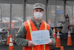 Staff Sgt. Zachary Heberlein, assigned to the 107th Attack Wing of the New York Air National Guard, holds up a sign he uses to communicate with residents at a drive-thru COVID-19 testing site in Buffalo, New York, May 5, 2020.