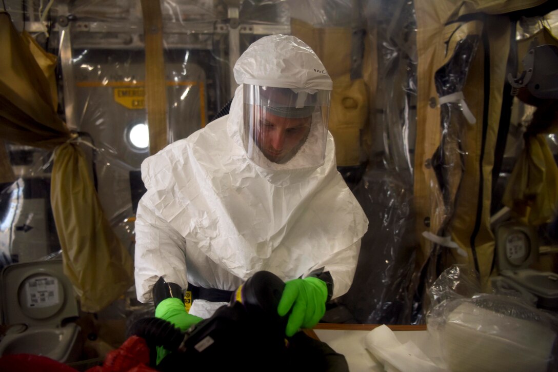 An airman in protective gear cleans an air respirator.