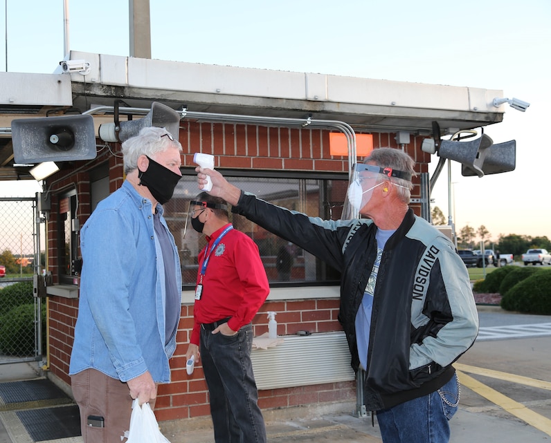Michael McCarty, right, supervisor, Production Plant Albany, Marine Depot Maintenance Command, uses a thermal scanner as part of a screening process plant employees must submit to each day as they return to their workplace while at Marine Corps Logistics Base Albany, Georgia, May 7.