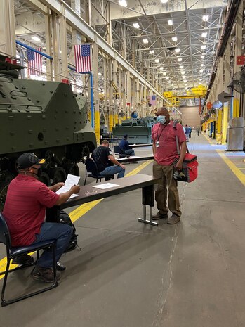 Reginald Fluellen, left, supervisor, Production Plant Albany, Marine Depot Maintenance Command, screens employees as part of a comprehensive plan to safeguard the health and welfare of those returning to the workplace.