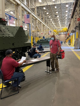 Reginald Fluellen, left, supervisor, Production Plant Albany, Marine Depot Maintenance Command, screens employees as part of a comprehensive plan to safeguard the health and welfare of those returning to the workplace.