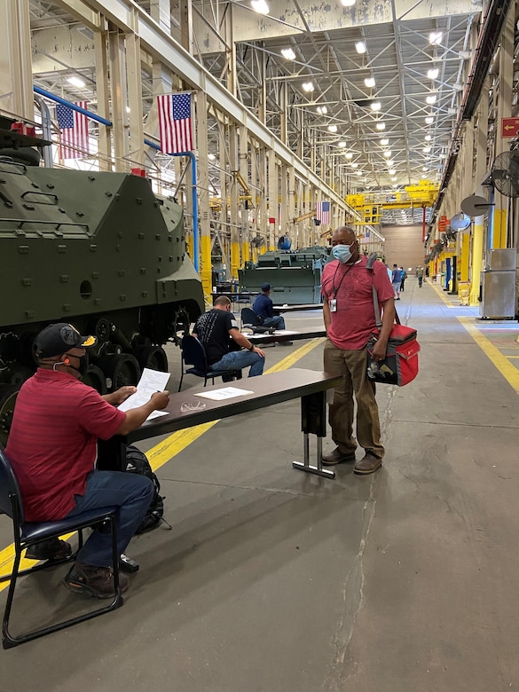 Reginald Fluellen, left, supervisor, Production Plant Albany, Marine Depot Maintenance Command, screens employees as part of a comprehensive plan to safeguard the health and welfare of those returning to the workplace.