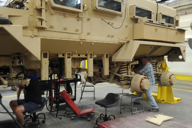 Heavy mobile equipment mechanics, Todd Jones, left, and Randy Kelly, right, Production Plant Albany, Marine Depot Maintenance Command, perform maintenance on a Mine-Resistant Ambush-Protected vehicle while adhering to social distance standards as well as the proper wear of face coverings.
