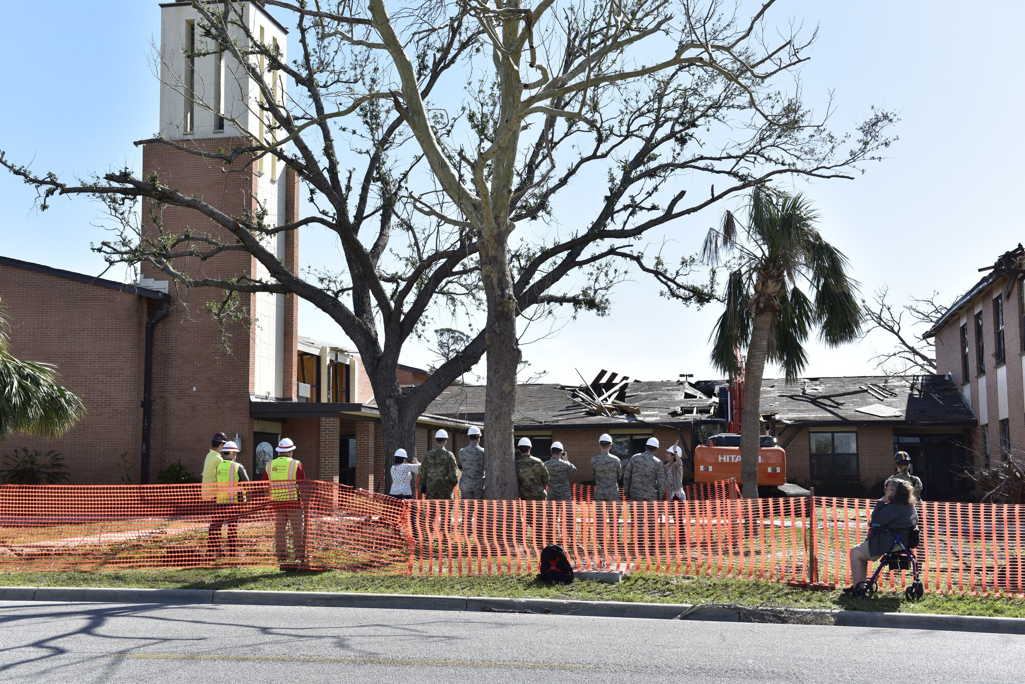 Contractors and Airmen watch as an excavator begin the demolition of the base chapel after it sustained major damage after Hurricane Michael at Tyndall Air Force Base, Fla., Feb. 11, 2019.