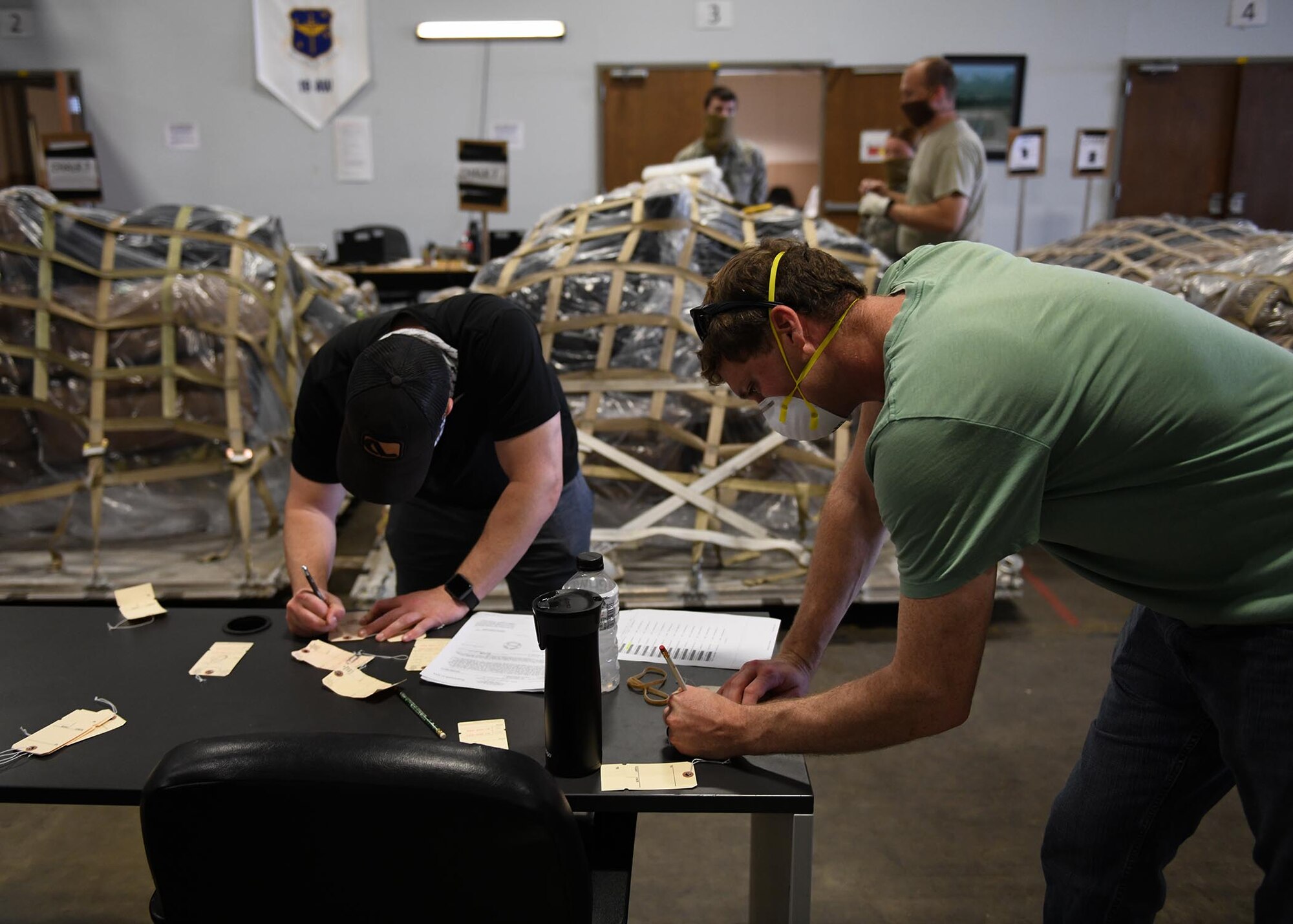 Individuals prepare tags and pallets of cargo for deploying personnel.