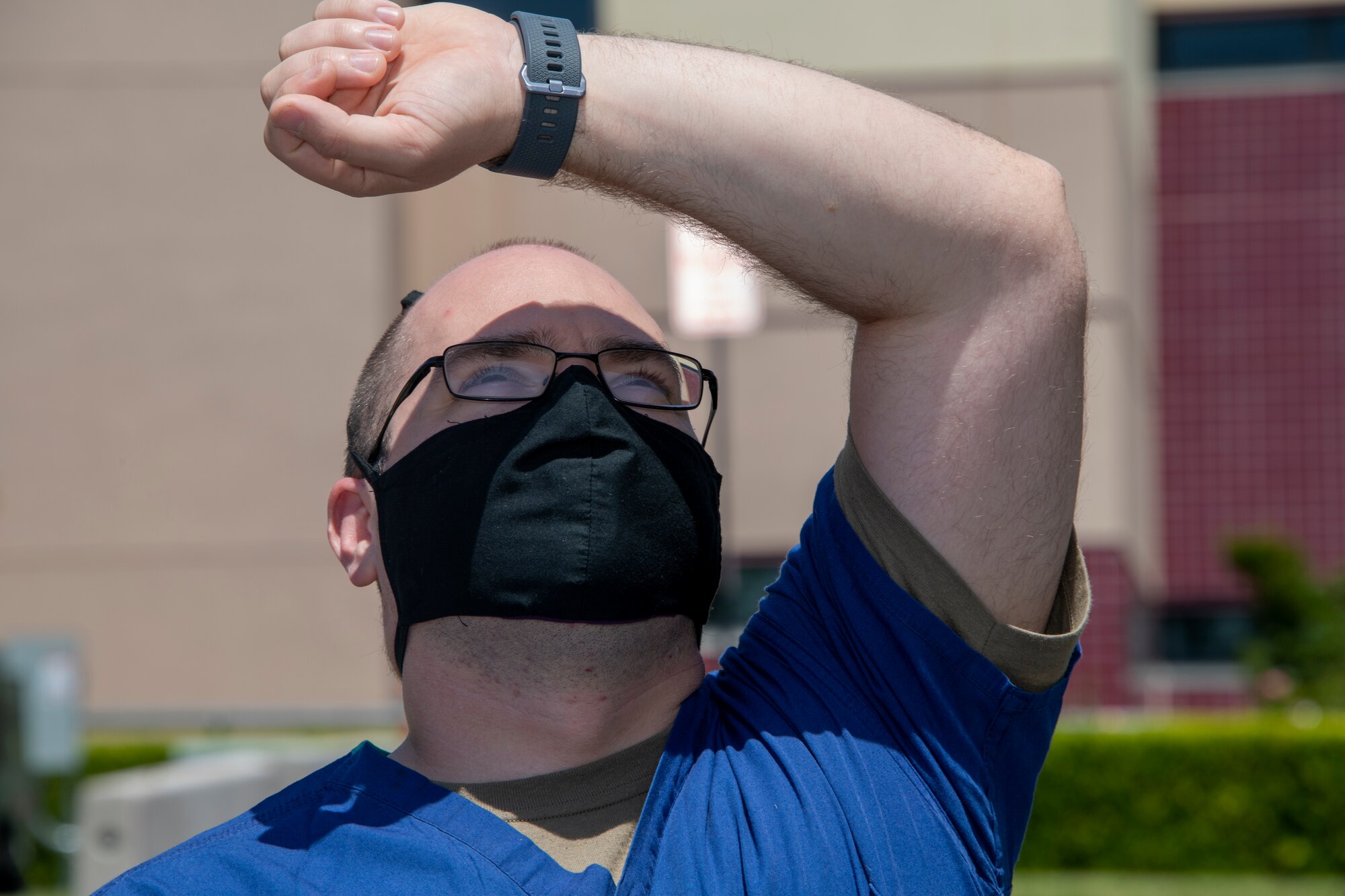 U.S. Air Force Staff Sgt. Christopher Allard, 60th Inpatient Operations Squadron shift supervisor, blocks the sun to watch the Operation American Resolve flyover May 9, 2020, at Travis Air Force Base, California. The flyover featured four T-38A Talons that are assigned to the 9th Reconnaissance Wing at Beale AFB, California, and was conducted to salute healthcare workers and first responders in Northern California cities impacted by COVID-19. (U.S. Air Force photo by Tech. Sgt. James Hodgman)