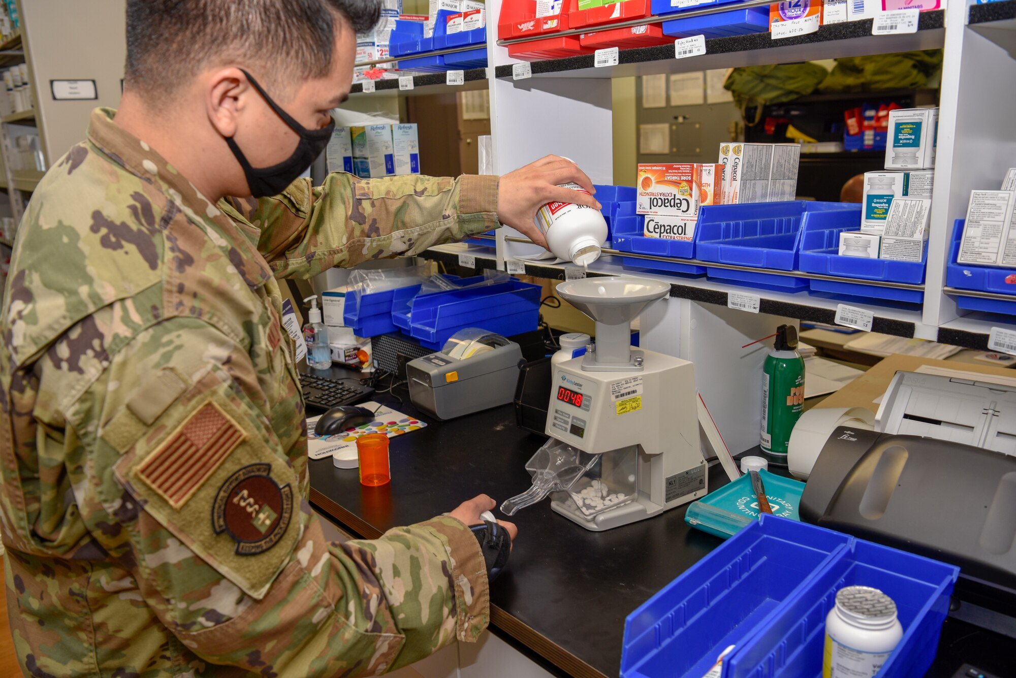 U.S. Air Force Staff Sgt. Albert Vallejo, 8th Medical Support Squadron pharmacy technician, pours medication through a pill counting machine at Kunsan Air Base, Republic of Korea, May 6, 2020. The pharmacy team has a goal time of 20 minutes to fill a prescription to provide a better customer service experience. (U.S. Air Force photo by Tech. Sgt. Joshua Arends)