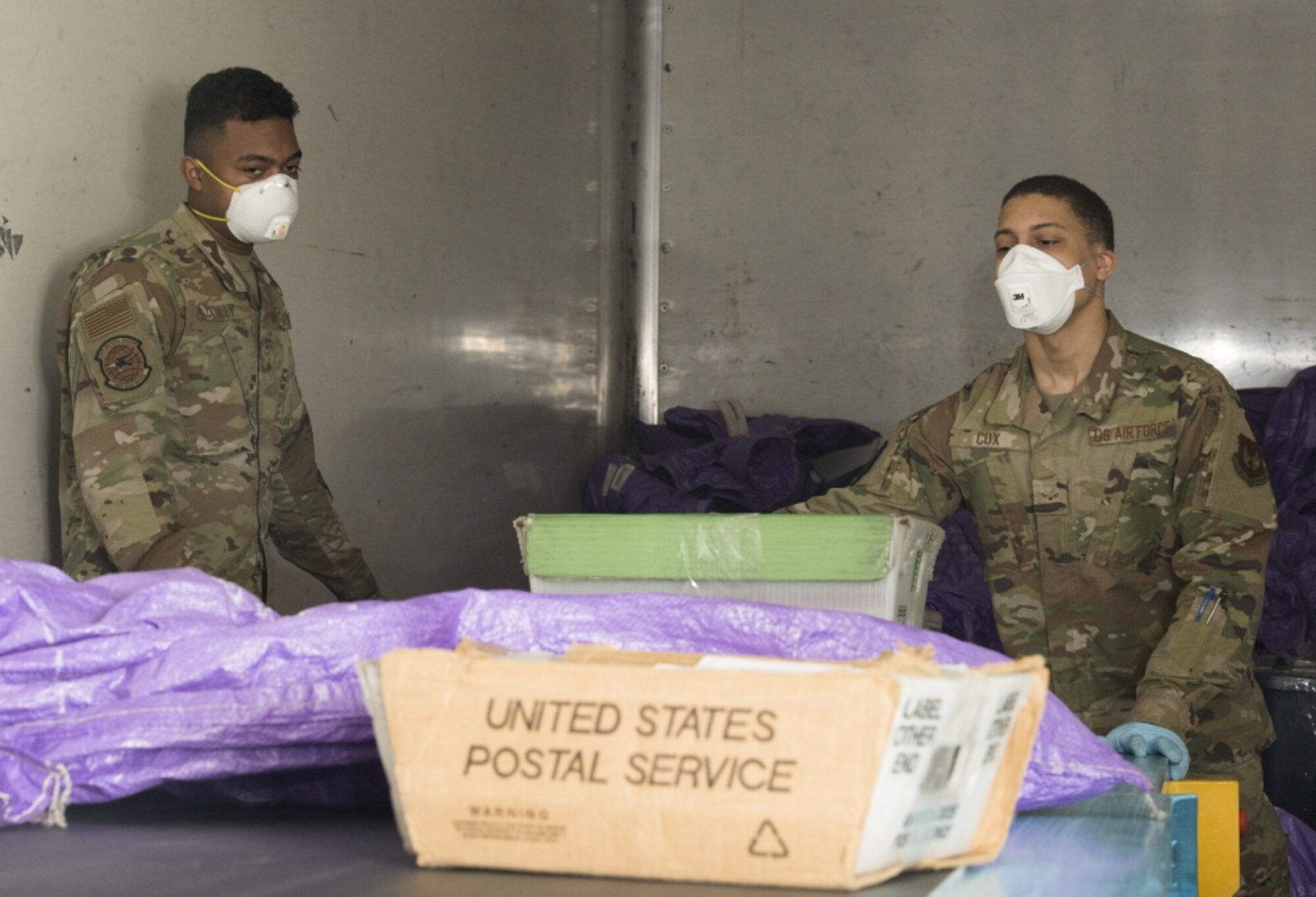 U.S. Air Force Airman 1st Class Andrew Cauley (left) and Airman 1st Class Aaren Cox (right), mail processing specialists with the USAFE-AFAFRICA Air Postal Squadron, Detachment Five, prepare packages for transportation from RAF Alconbury, England on April 10, 2020. The Detachment Five postal team continue to maintain operational readiness during COVID 19 as the central postal distribution hub for U.S. service members stationed in the United Kingdom. (U.S. Air Force photo by Master Sgt. Brian Kimball)