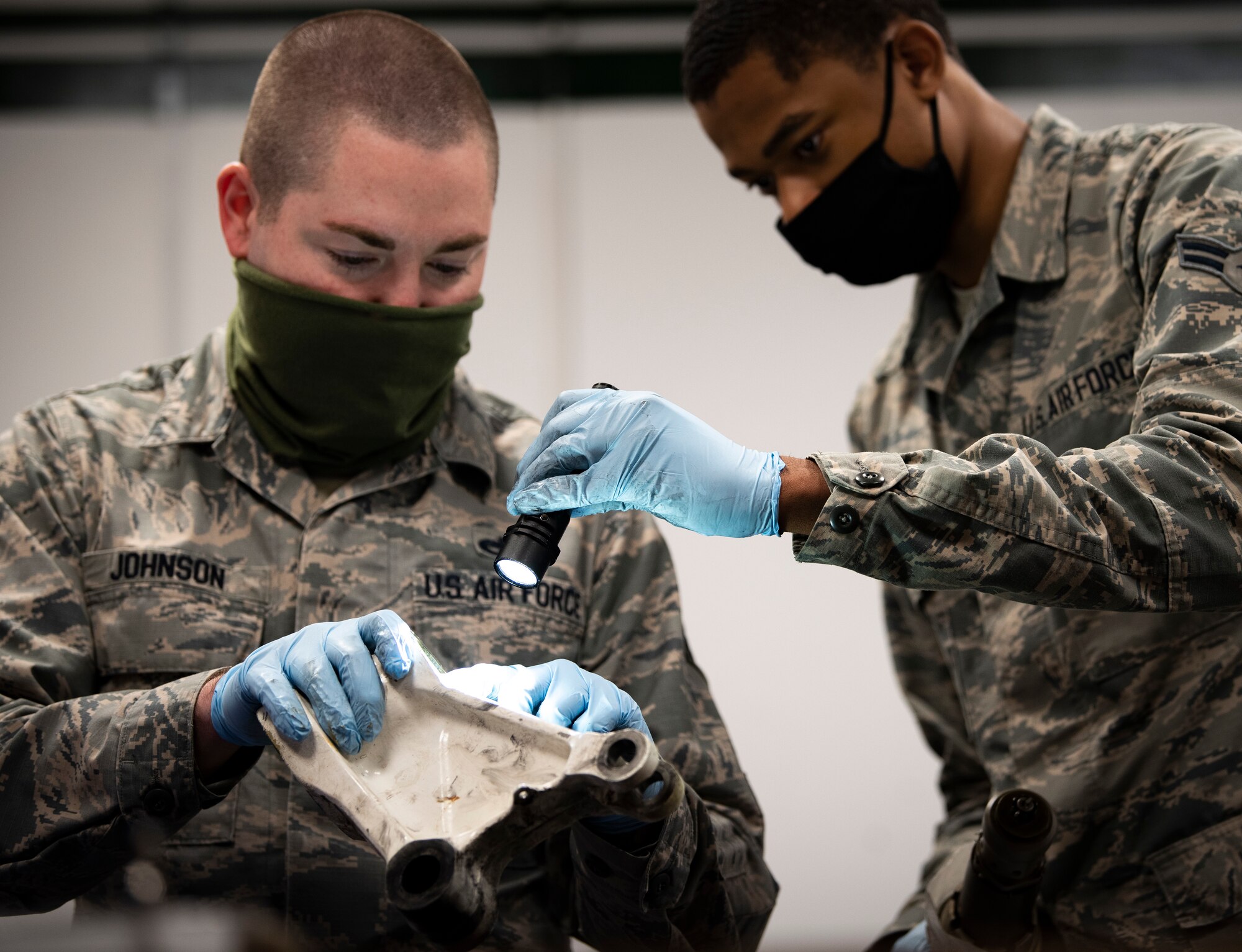 Hydraulic systems Airmen assigned to the 48th Maintenance Group inspect parts while wearing personal protective equipment to combat the spread of COVID-19 at Royal Air Force Lakenheath, England, April 30, 2020. The hydraulics shop is one of many units that helped the 48th MXG earn the 2019 USAFE-AFAFRICA Clements McMullen Memorial Daedalian Weapon System Maintenance Trophy. (U.S. Air Force photo by Airman 1st Class Madeline Herzog)