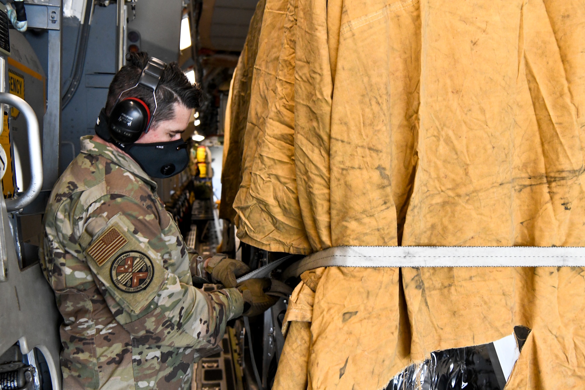 Senior Master Sgt. Andrew Silkworth, 436th Aerial Port Squadron airfreight superintendent, tightens a cargo strap at Dover Air Force Base, Delaware, April 30, 2020. Tarps were placed on top of the Transport Isolation Systems due to inclement weather at Dover AFB. In accordance with health protection policies, Dover AFB will serve as the sole hub for TIS decontamination on the East Coast.  (U.S. Air Force photo by Senior Airman Christopher Quail)