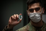 U.S. Air Force Senior Airman Bernabe Aguero, from the 177th Fighter Wing, New Jersey National Guard, shows the challenge coin presented to him by New Jersey State Command Chief Master Sgt. Michael Rakauckas at the New Jersey Veterans Home at Paramus, N.J., May 7, 2020.