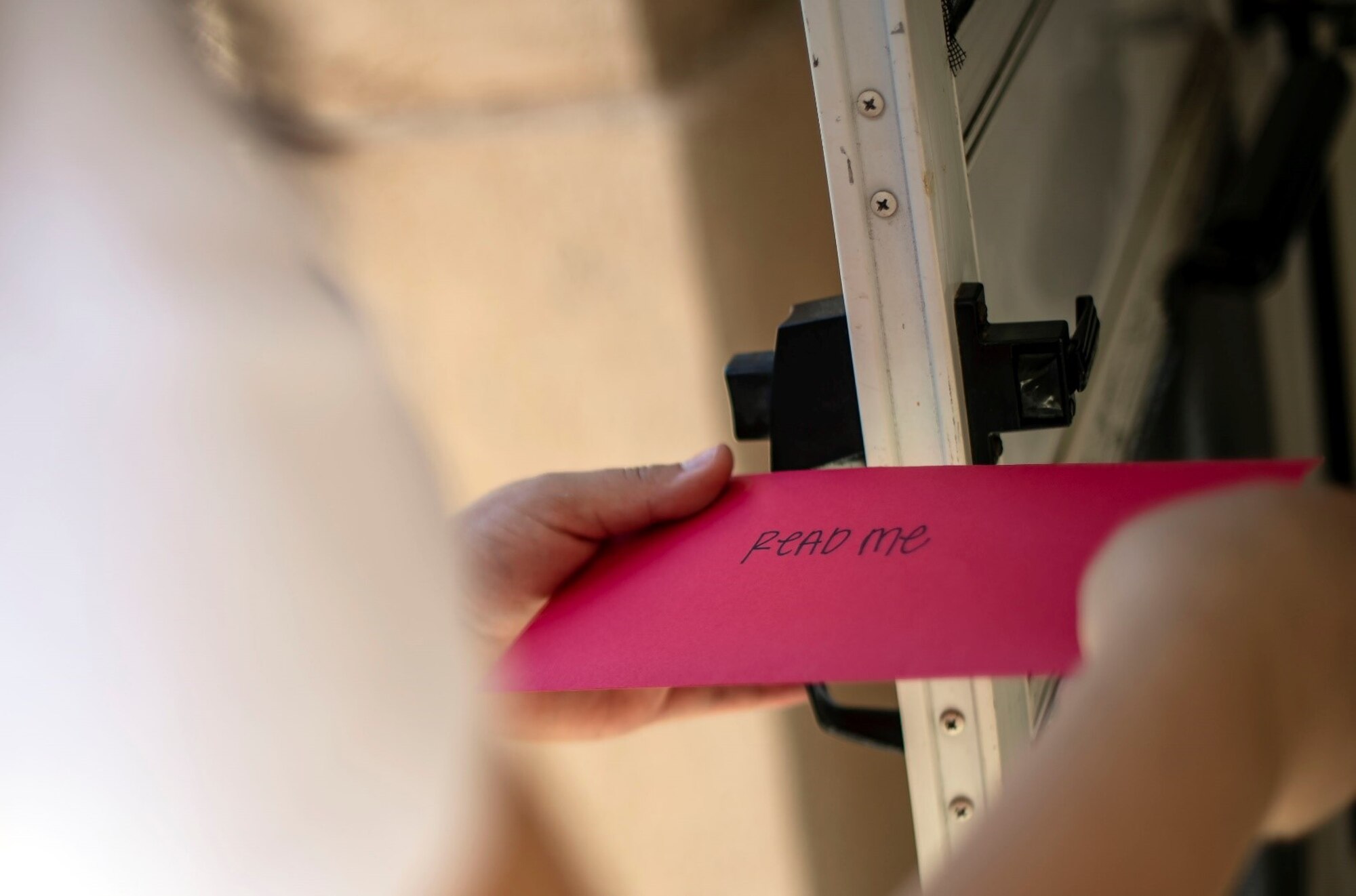 A woman holds a pink envelope with the words "read me" on it.