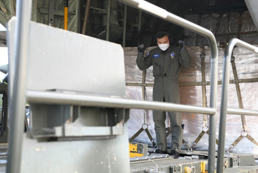 A South Korean aircrew member directs an unloading truck to the back of a Republic of Korea C-130 aircraft at Joint Base Andrews, Md., May 12, 2020. Airmen assigned to the 89th Airlift Wing and Korean aircrew offloaded protective masks from the aircraft. (U.S. Air Force photo by Airman 1st Class Spencer Slocum)