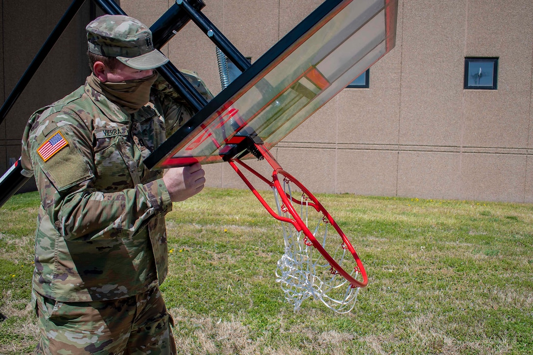 A soldier assembling a basketball net.